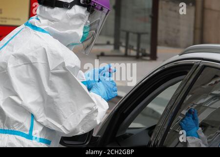 A Coruna-Spain -August 18, 2020: Ein Mitarbeiter im Gesundheitswesen verwendet einen PCR-Test (Mund- und Nasenabstrich) auf eine Person in einem Auto, um die Anwesenheit oder Abwesenheit zu bestimmen Stockfoto