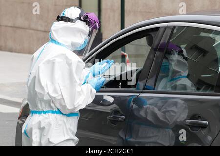A Coruna-Spain -August 18, 2020: Ein Mitarbeiter im Gesundheitswesen verwendet einen PCR-Test (Mund- und Nasenabstrich) auf eine Person in einem Auto, um die Anwesenheit oder Abwesenheit zu bestimmen Stockfoto