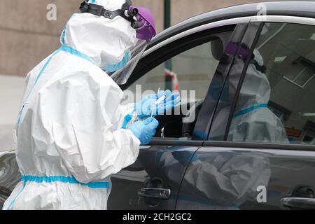 A Coruna-Spain -August 18, 2020: Ein Mitarbeiter im Gesundheitswesen verwendet einen PCR-Test (Mund- und Nasenabstrich) auf eine Person in einem Auto, um die Anwesenheit oder Abwesenheit zu bestimmen Stockfoto