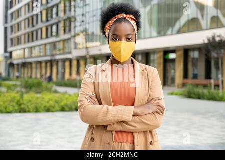 Junge zeitgenössische afrikanische Geschäftsfrau in Casualwear und Schutzmaske Stockfoto