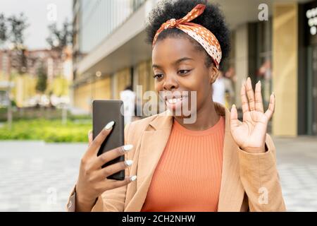 Junge Frau afrikanischer Ethnie, die ihre Freundin anschaut Smartphone-Display Stockfoto
