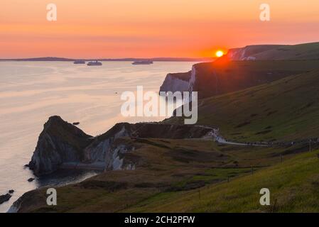 Durdle Door, West Lulworth, Dorset, Großbritannien. September 2020. Wetter in Großbritannien. Der Himmel leuchtet orange bei Sonnenuntergang über der Jurassic Coast bei Durdle Door bei West Lulworth in Dorset und blickt auf die leeren Kreuzfahrtschiffe, die in Weymouth am Ende eines heißen Tages bei Sonnenschein während der Mini-Hitzewelle vor Anker liegen. Bild: Graham Hunt/Alamy Live News Stockfoto