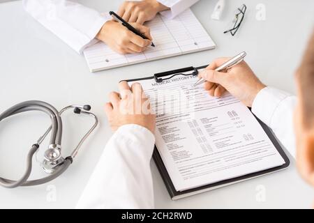 Hände von jungen Arzt mit Stift Füllung in der Krankengeschichte Patientenformen Stockfoto