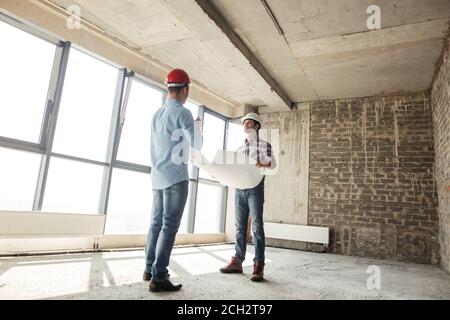 Low-Angle-Ansicht. Ein Team von Bauherren diskutieren einen Bauplan in Innenräumen Stockfoto