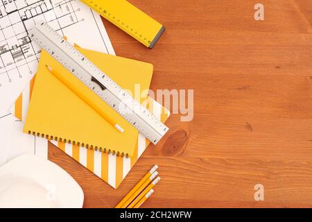 Flatlay von Copybooks, Linealen und Bleistiften durch ausgeklappte Blaupausen mit Skizzen Stockfoto