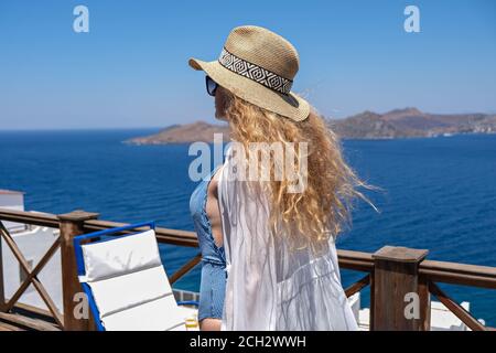 Schöne junge Frau in Badeanzug weißes Kleid und Strohhut Auf der weißen Terrasse Balkon des Hauses oder Hotels mit Meer Anzeigen Stockfoto