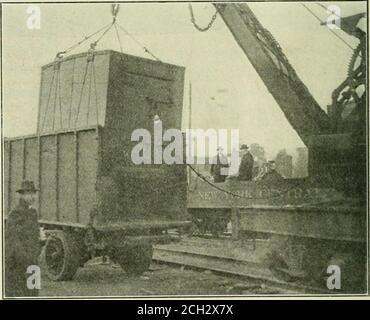 . Eisenbahnmechaniker . Ein Lokomotivkran stellt einen beladenen Container auf dem Auto ein von den Schwierigkeiten, die im Betrieb von diesem System begegnet werden, wird der Mangel von der angemessenen Aufhebungsvorrichtung auf den Räumen von vielen Spediteuren sein, die das Anbinden von einem Kraftfahrzeug erfordern, während der Container entladen und wieder beladen wird. Andere Schwierigkeiten, die überwunden werden müssen, sind: Die Möglichkeit der Streuung der Behälter zu breit ein Gebiet und die wahrscheinliche Mangel an ausreichenden Anzug-. Ein beladener Container, der aus dem LKW-fähigen Verkehr in eine Richtung gehoben wird. Diese Einwände Stockfoto