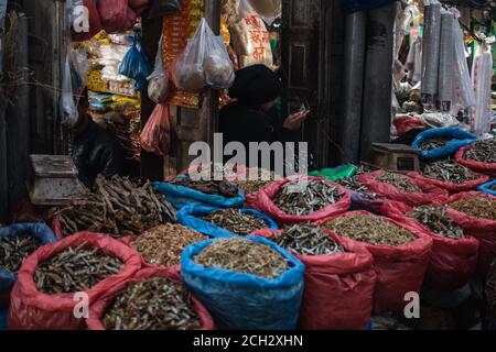 Kathmandu, Nepal - Dezember 22 2019: Zwei nicht identifizierte Anbieter verkaufen getrockneten Fisch und andere Verbrauchsmaterialien auf einem lokalen Straßenmarkt in Kathmandu, Dezember Stockfoto