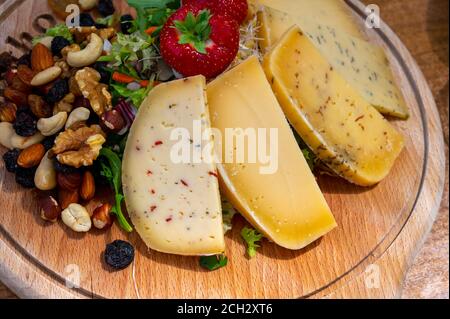Verkostung Holzbrett mit verschiedenen Arten von belgischen Hartabtei Käse, Nüsse und Früchte aus nächster Nähe Stockfoto