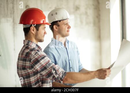 Planungs- und Managementfähigkeiten.Ingenieure beaufsichtigen den Bau eines neuen Hauses. Seitenansicht Foto Stockfoto