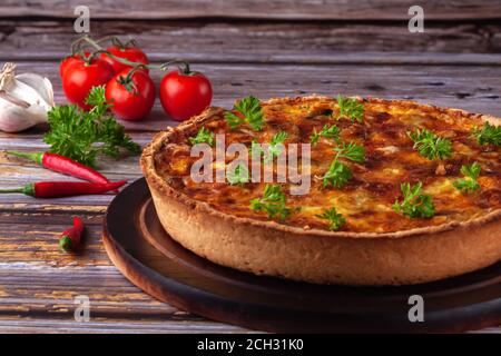 Französische Quiche mit Huhn und Pilzen auf Holzgrund Stockfoto