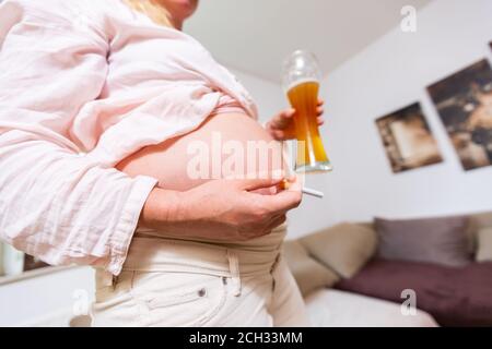 Eine schwangere Frau mit einem Bier und einer Zigarette Ihre Hand Stockfoto