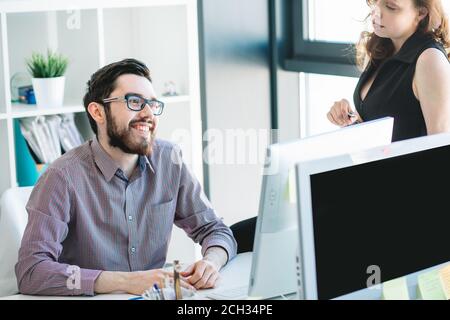 Web-Programmierer tragen Brille und Shirt sitzt am Schreibtisch in fröhlicher Stimmung. Job gut gemacht Stockfoto