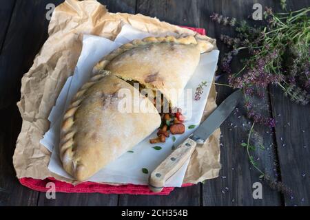 Italienische Pizza Calzone mit Pilzen, Spinat und Käse auf einer Holzoberfläche mit einem Bündel Thymian, rustikalen Stil, selektive Fokus Stockfoto