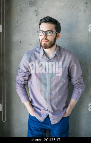 Nahaufnahme Bild von wunderschönen Kerl in casual Outfit hält seine Hände auf Taschen und Blick auf die Kamera Stockfoto