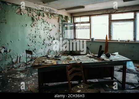 Gruselig verlassene Bürozimmer mit altem Holztisch und Fenstern. Horror-Konzept. Stockfoto