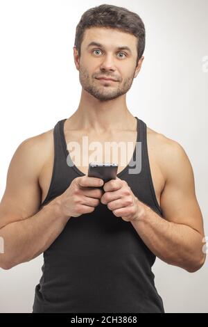 Nahaufnahme Porträt von wunderschönen Mann in Singlet mit Handy. Neue Technologie-Konzept Stockfoto