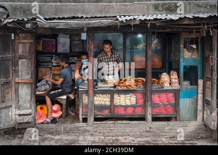 KATHMANDU, NEPAL - 14. AUGUST 2018: Nicht identifizierte nepalesische Männer verkaufen Lebensmittel in einem Geschäft in der Straße von Kathmandu, Nepal Stockfoto