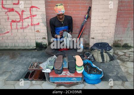 KATHMANDU, NEPAL - 14. AUGUST 2018: Nicht identifizierter nepalesischer Schuster sitzt in der Straße von Kathmandu, Nepal Stockfoto