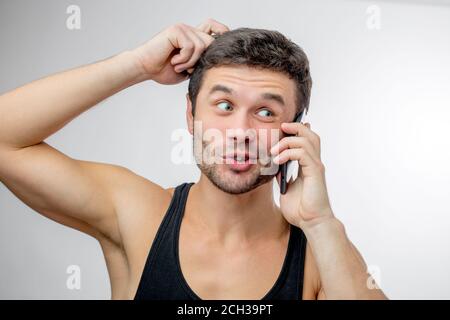 Pensive Kerl in Singlet mit Smartphone. Lassen Sie mich think.choice Konzept Stockfoto