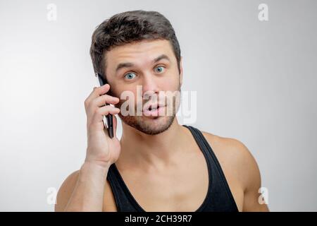 Nahaufnahme Porträt eines netten Mannes mit weit offen Augen mit seinem Handy.Sprechen Sie mit Kunden Stockfoto