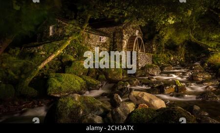 Das Old Mill Cottage auf Combe Gill in Borrowdale, Lake District, Großbritannien. Nachts mit Fackelschein bei langer Belichtung aufgenommen. Stockfoto