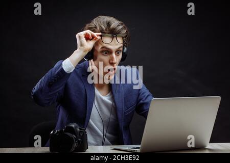 Nahaufnahme Foto der braunhaarige Fotograf mit geöffnetem Mund und weit geöffneten Augen am Notebook lookig. emotionale Kollege. überraschung Konzept Stockfoto