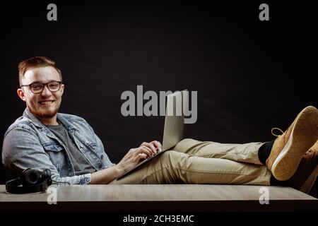 Nahaufnahme Portrait von Happy Geschäftsmann in lässig-eleganten Textilien mit dem Net bei der Arbeit und das Sitzen mit gekreuzten Beinen Stockfoto