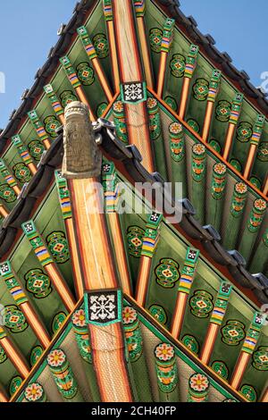 Detail der lebendigen Farben der traditionell bemalten Holzbalken und geschwungenen Pagodenüberhänge im Changdeokgung Palast in Seoul, Südkorea. Der Changdeokgung Palast war 270 Jahre lang die private Residenz der koreanischen Kaiser. Stockfoto