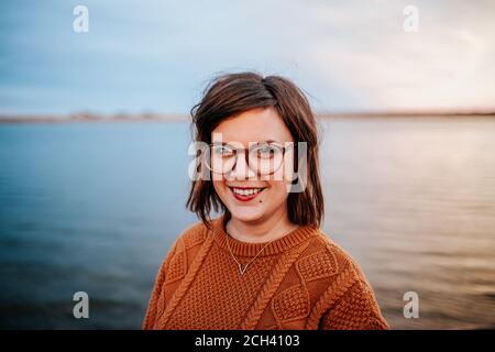 Mitte Porträt einer Frau mit Brille in der Nähe eines Sees Stockfoto