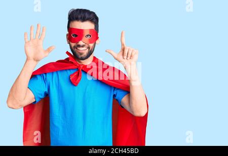 Junger schöner Mann mit Bart trägt Superhelden Kostüm zeigt und zeigt mit den Fingern Nummer sieben, während lächelnd zuversichtlich und glücklich. Stockfoto