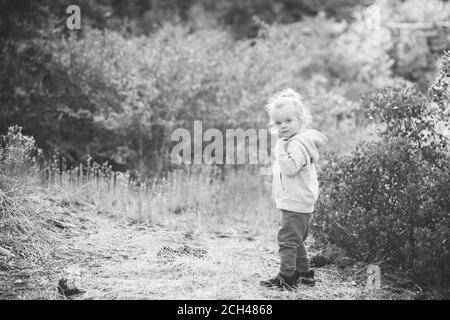 Schwarz-Weiß-Fotografie eines 2-jährigen Kleinkindes, das auf einem Naturspaziergang mit ihrer Mama am Happy Hills Trail in Big Bear, Kalifornien posiert. Stockfoto