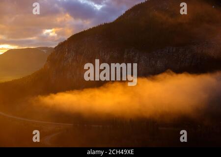 Frühlingsaufgang mit Nebel und Orangenhimmel, Kananaskis, Alberta, Kanada. Stockfoto