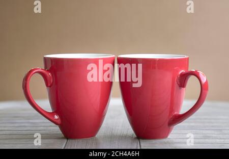 Zwei rote Tassen auf Holztisch. Isoliert. Stockfoto