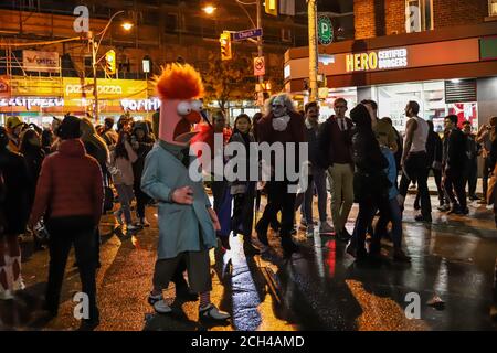 Halloween Nacht Karneval . Kirche Straße, Menschen zu Fuß in verschiedenen Masken und Kostümen. Stockfoto