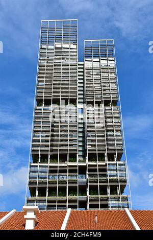 Kontrastierende Architektur eines modernen mehrstöckigen Wohnblocks und Die roten Terrakotta-Dachziegel eines alten Kolonialgebäudes Stockfoto