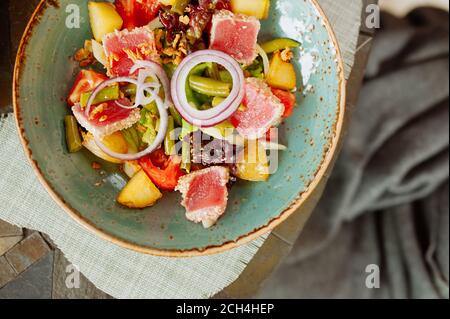 Gegrillter Thunfisch-Gemüsesalat in einem stilvollen Keramik blauen Teller, schönes Essen im Restaurant, Draufsicht Stockfoto