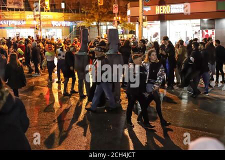 Halloween Nacht Karneval . Kirche Straße, Menschen zu Fuß in verschiedenen Masken und Kostümen. Stockfoto