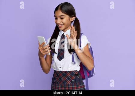 Lächelnd indisches Schulmädchen Video Anruf auf Handy isoliert auf Hintergrund. Stockfoto