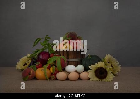 Stillleben porträtiert kalifornische Ernte im Sommer geerntet, Eier und mit Sonnenblumen verziert, auf braunem Hintergrund, Seitenansicht mit Kopierraum Stockfoto