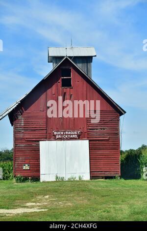 Lacon, Illinois, USA. Eine alte rote, hölzerne Scheune sitzt inmitten eines Kornfeldes entlang einer Landstraße. Stockfoto