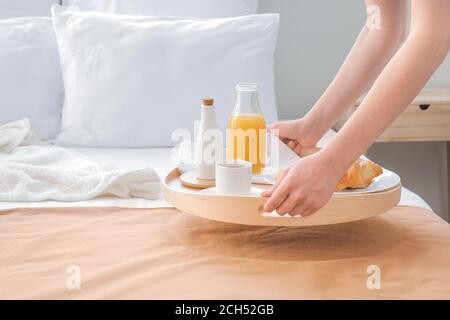 Zimmermädchen, die ein leckeres Frühstück auf dem Bett im Hotelzimmer serviert Stockfoto