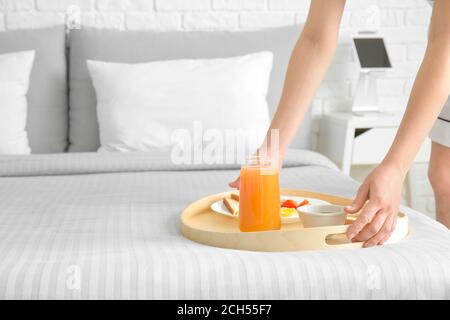 Zimmermädchen, die ein leckeres Frühstück auf dem Bett im Hotelzimmer serviert Stockfoto