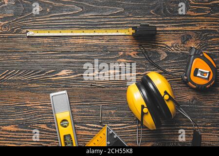 Maßband mit Baumaterial auf Holzhintergrund Stockfoto