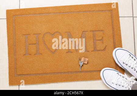 Türmatte mit Schlüssel aus dem Haus und Schuhe auf dem Boden Stockfoto