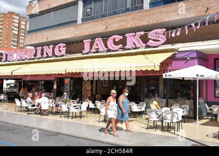 Benidorm, Spanien. September 2020. Frauen mit Gesichtsmasken gehen an Jumping Jack's Bar vorbei, inmitten der Krise des Coronavirus (COVID-19).als Spanien im März einsperrte, um das Coronavirus zu verlangsamen, genossen etwa 25,000 britische Touristen die Strände und Bars der Costa Blanca in Benidorm. Die örtlichen Beamten befahlen schnell, dass die Hotels ihre Türen schließen sollten, und als die Besucher ihre Koffer packten und zum Flughafen strömten, ging die Tourismusindustrie der Stadt mit ihrem Lebenselixier zusammen mit dem Rest des Landes in den Winterschlaf. Kredit: Juan Zamora/SOPA Images/ZUMA Wire/Alamy Live Nachrichten Stockfoto