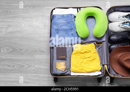 Offener verpackter Koffer auf Holzhintergrund. Reisekonzept Stockfoto