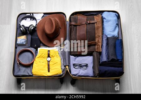 Offener verpackter Koffer auf Holzhintergrund. Reisekonzept Stockfoto