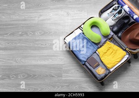 Offener verpackter Koffer auf Holzhintergrund. Reisekonzept Stockfoto