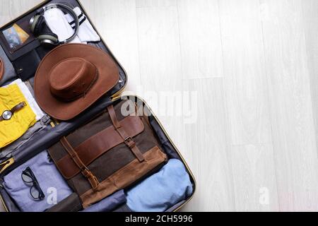 Offener verpackter Koffer auf Holzhintergrund. Reisekonzept Stockfoto